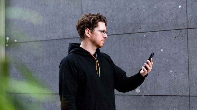 Eine Person hält ein iPhone 12 in der Hand, um es per Face ID zu entsperren.