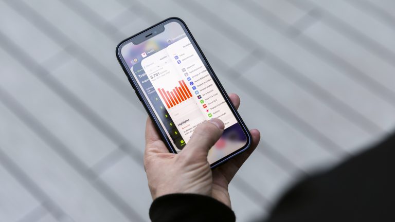 Eine Person hält ein iPhone 12 in der Hand. Darauf ist der sogenannte App-Umschalter zu sehen, der alle geöffneten Apps anzeigt.