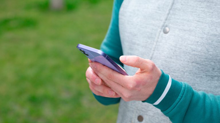 Eine Person hält ein iPhone in der Hand und tippt darauf.