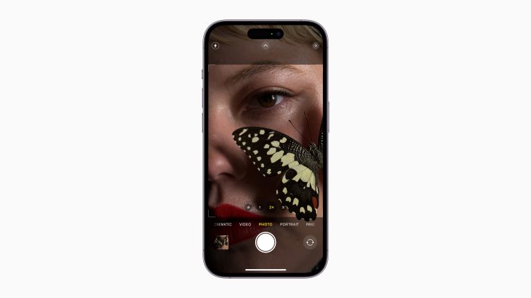 Ein iPhone 14 Pro von vorne, auf dem gerade die Kamera-App geöffnet ist und ein Gesicht einer Frau zeigt.