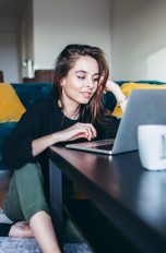 Amazon Prime kündigen Eine Person sitzt auf dem Boden vor einem Tisch und bedient einen Laptop.