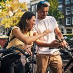 Zwei Personen auf Fahrr&auml;dern machen eine kurze Pause und schauen gemeinsam auf ein Smartphone.