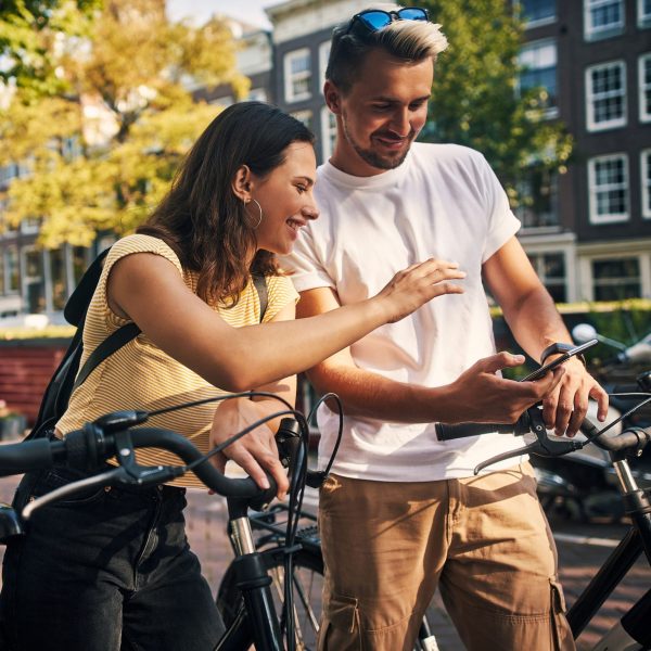 Zwei Personen auf Fahrr&auml;dern machen eine kurze Pause und schauen gemeinsam auf ein Smartphone.