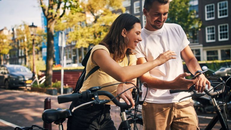 Zwei Personen auf Fahrrädern machen eine kurze Pause und schauen gemeinsam auf ein Smartphone.
