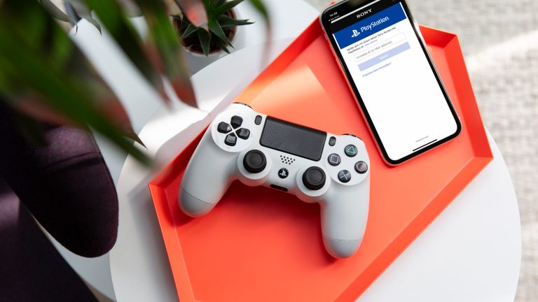 Ein PS4-Controller liegt neben einem iPhone auf einer Schale.