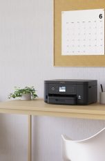 Ein Epson-Drucker steht auf einem Schreibtisch neben einem Laptop.