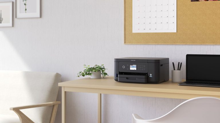 Ein Epson-Drucker steht auf einem Schreibtisch neben einem Laptop.