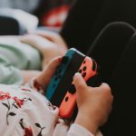 Ein Kind h&auml;lt zwei Joy-Cons von Nintendo in ihrer Halterung in der Hand.