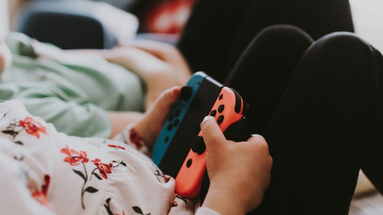 Ein Kind hält zwei Joy-Cons von Nintendo in ihrer Halterung in der Hand.