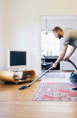 Eine Person saugt den versiegelten Parkettboden in einem Wohnzimmer.