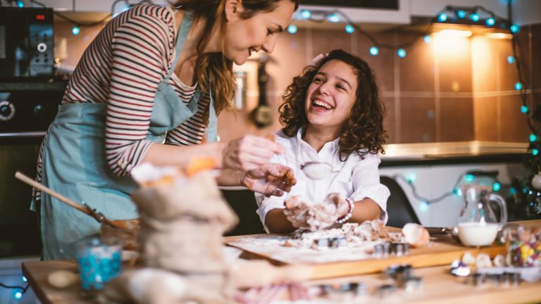 Mutter und Tochter stehen in der K&uuml;che und kneten Teig.