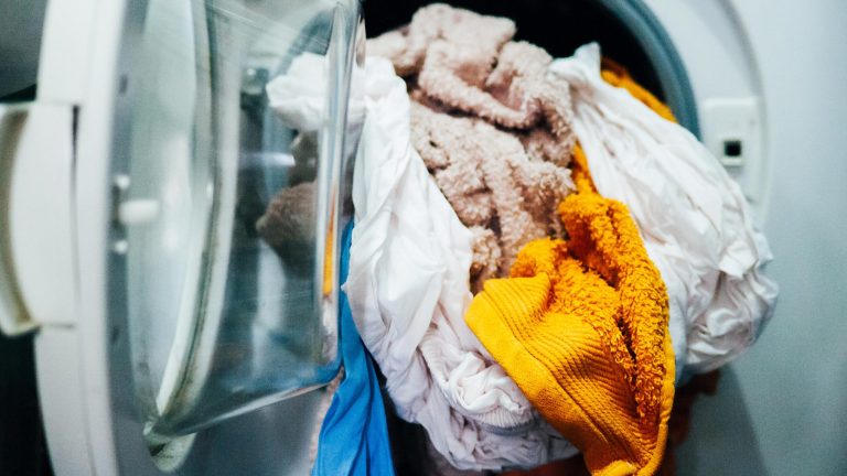 In einer geöffneten Waschmaschine liegen nasse Bettlaken und Handtücher.