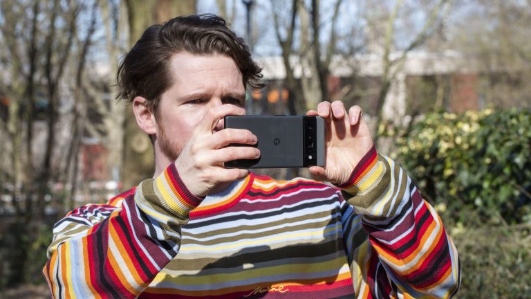 Eine Person hält ein Google Pixel in der Hand und macht damit draußen ein Foto.