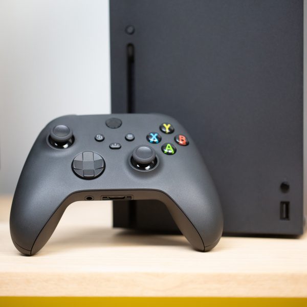 Ein Xbox Wireless Controller ist an eine Xbox Series X gelehnt.