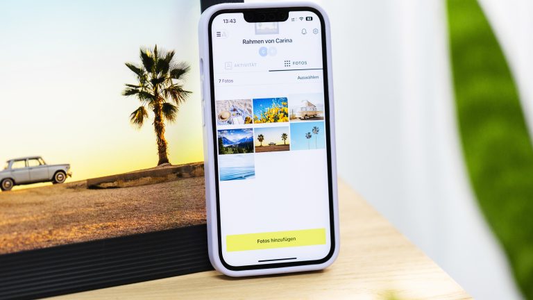 Ein Smartphone lehnt an einem digitalen Bilderrahmen. Auf beidem sind Urlaubsfotos zu sehen. aura-bilderrahmen-0015