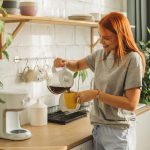 Eine Person gie&szlig;t etwas Kaffee aus einer Filtermaschine in eine Tasse.