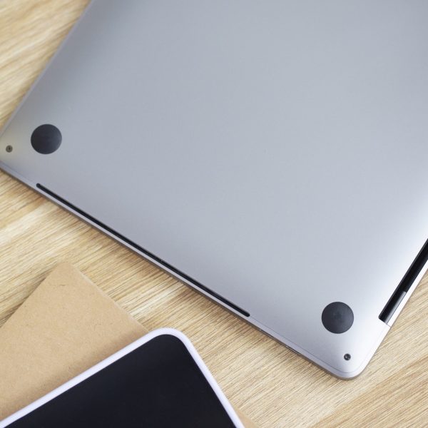 Ein umgedrehtes MacBook liegt auf einem Tisch. Zu sehen sind die schmalen L&uuml;ftungsschlitze.