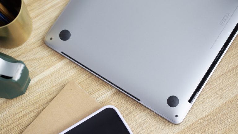 Ein umgedrehtes MacBook liegt auf einem Tisch. Zu sehen sind die schmalen L&uuml;ftungsschlitze.