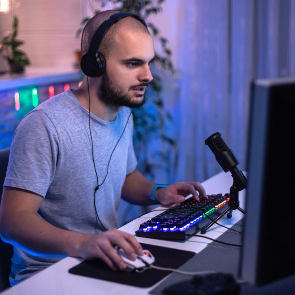 Eine Person sitzt vor einem Gaming-Rechner und spielt etwas.