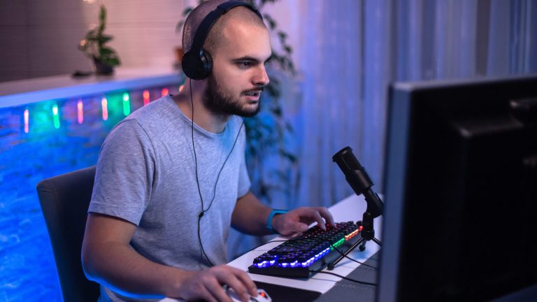 Eine Person sitzt vor einem Gaming-Rechner und spielt etwas.