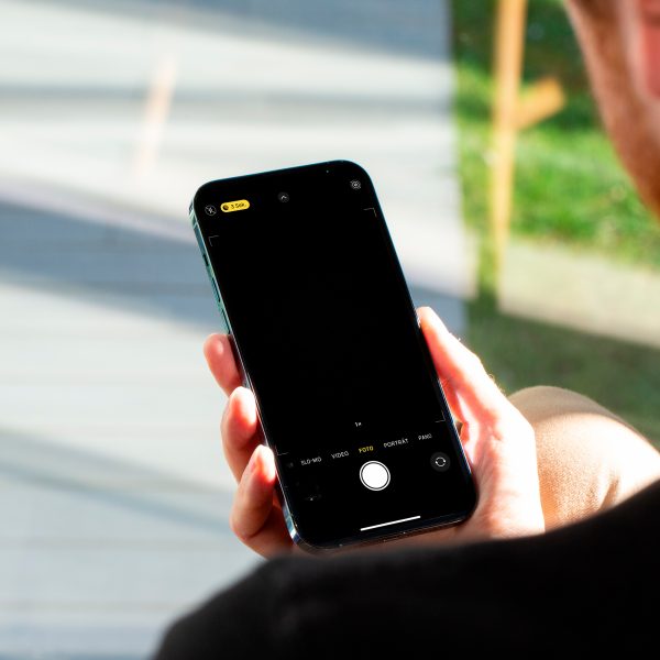 Eine Person blickt auf ein iPhone, welches sie in der rechten Hand h&auml;lt.