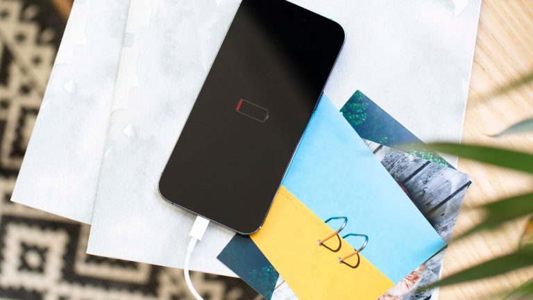 Ein iPhone liegt auf einem Regal, ist an den Strom angesteckt und zeigt den Akku-Balken auf dem Bildschirm an.