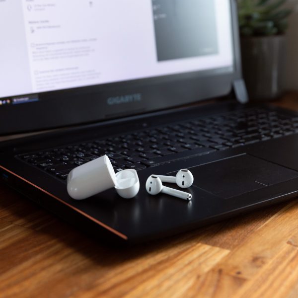 AirPods und das dazugeh&ouml;rige Case liegen auf einem Windows-Laptop.