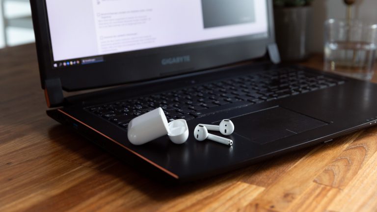 AirPods und das dazugehörige Case liegen auf einem Windows-Laptop.