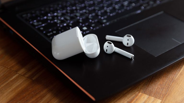 Nahaufnahme von AirPods mit Case, die auf einem Windows-Laptop liegen.