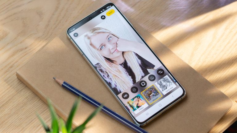Ein Android-Smartphone liegt auf einem Notizbuch, das sich wiederum auf einem Tisch befindet. Auf dem Display ist ein Portrait zu sehen, das mit der App “Facetune“ bearbeitet wurde.