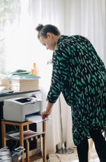 Eine Person steht vor einem Drucker und nimmt einen Ausdruck heraus.