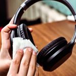 Eine Person wischt mit einem Tuch &uuml;ber die Ohrmuschel eines On-Ear-Kopfh&ouml;rers.