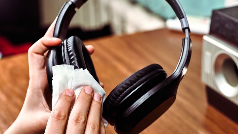 Eine Person wischt mit einem Tuch über die Ohrmuschel eines On-Ear-Kopfhörers.