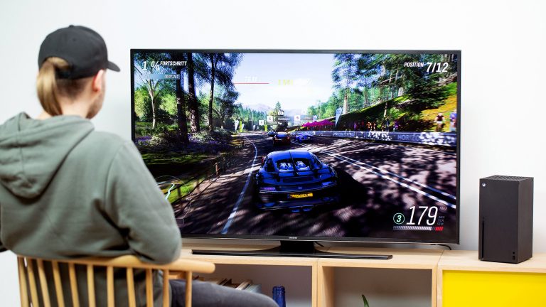 Eine Person sitzt vor einem Fernseher und spielt Forza Horizon auf einer Xbox Series X.