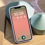 Ein iPhone lehnt an einen Dekotopf. Auf dem Gerät ist der Sperrbildschirm und das leuchtende Siri-Symbol zu erkennen.