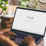 Eine Person sitzt vor einem Laptop, auf dem die Google-Suchleiste zu sehen ist.