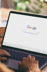 Eine Person sitzt vor einem Laptop, auf dem die Google-Suchleiste zu sehen ist.