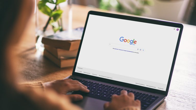 Eine Person sitzt vor einem Laptop, auf dem die Google-Suchleiste zu sehen ist.