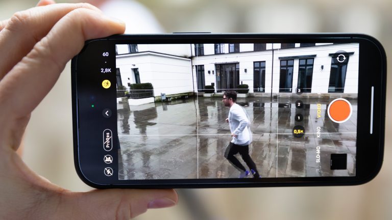 Ein iPhone 14 Pro mit eingeschaltetem Actionmodus filmt eine vorbeilaufende Person.