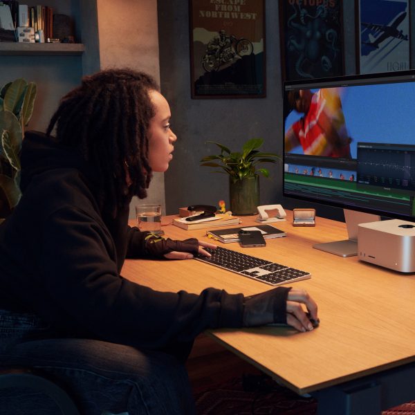 Eine Person sitzt an einem Schreibtisch vor einem Apple Studio Display.