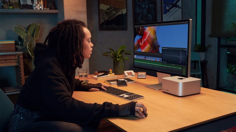 Eine Person sitzt an einem Schreibtisch vor einem Apple Studio Display.