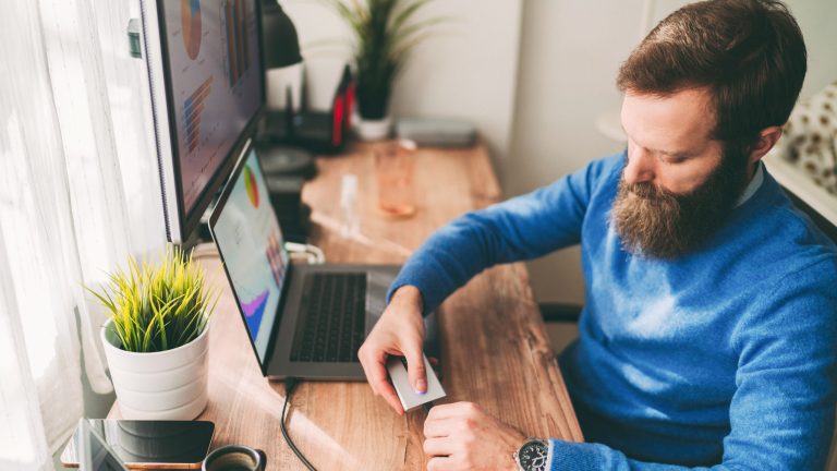 Eine Person steckt eine externe Festplatte an einen Laptop an.