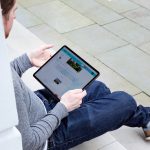Eine Person sitzt auf einer Treppenstufe und h&auml;lt ein iPad Pro in der Hand.