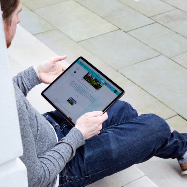 Eine Person sitzt auf einer Treppenstufe und hält ein iPad Pro in der Hand.