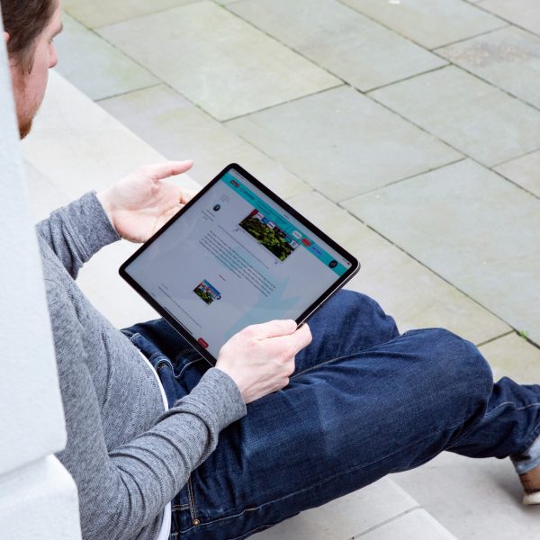 Eine Person sitzt auf einer Treppenstufe und h&auml;lt ein iPad Pro in der Hand.