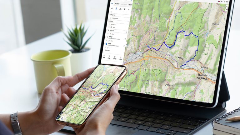 Eine Person hält ein Smartphone in der Hand und schaut auf ein Tablet. Auf beiden Geräten ist dieselbe Karte der Navi-App „Locus Map“ zu sehen.