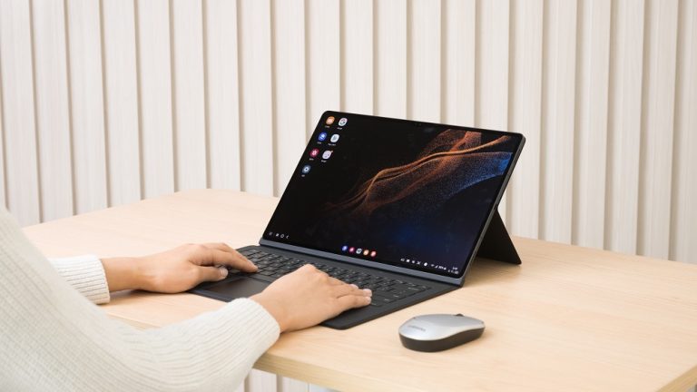 Ein Samsung Galaxy Tab S8 mit Book Cover auf einem Tisch. Eine Person tippt auf der Tastatur.