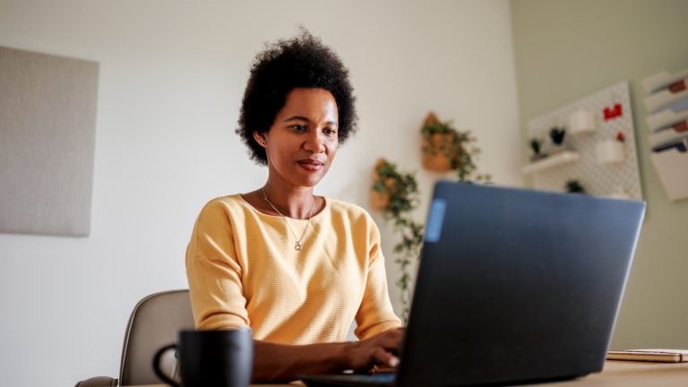 Eine Person sitzt vor einem Windows-Laptop und tippt auf der Tastatur.