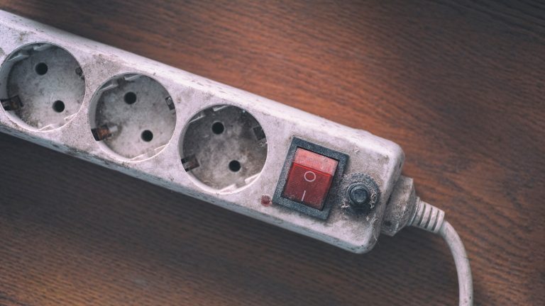 Detailansicht einer stark verschmutzten Steckdosenleiste.