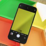 Ein iPhone mit ge&ouml;ffneter Kamera-App liegt auf bunten Schalen.